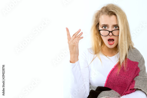 Young blond woman with glasses wrapped in a wide scarf posing on a white background