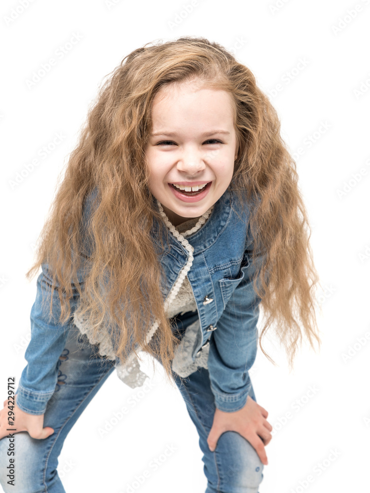 Cute little girl with wavy hair and in casual denim outfit smiling against white background Cute little girl with wavy hair and in casual denim outfit smiling against white background
