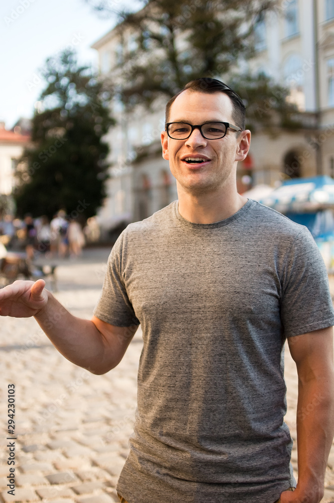 Outdoors portrait of an excited male tourist in the street with buildings of an old town in Europe in the background
