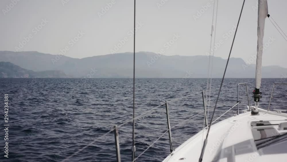 Someone is standing on front deck of white sailing yacht, enjoying gorgeous view of the Mediterranean Sea. Someone is standing on front deck of white sailing yacht, enjoying gorgeous view of the Mediterranean Sea.
