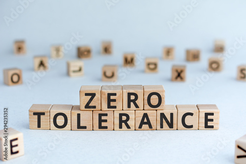 Zero tolerance - words from wooden blocks with letters, severely punishing all unacceptable behaviour, zero tolerance concept, random letters around, white  background