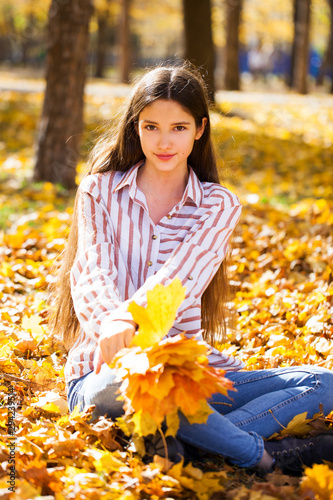 Portrait of a young beautiful girl with yellow maple leaves