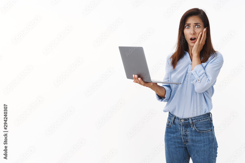Shocked concerned brunette adult woman with tattoo, panic, stare distressed worried camera, touch cheek ambushed, gasping anxious, hold laptop, delete file, receive bad news text message