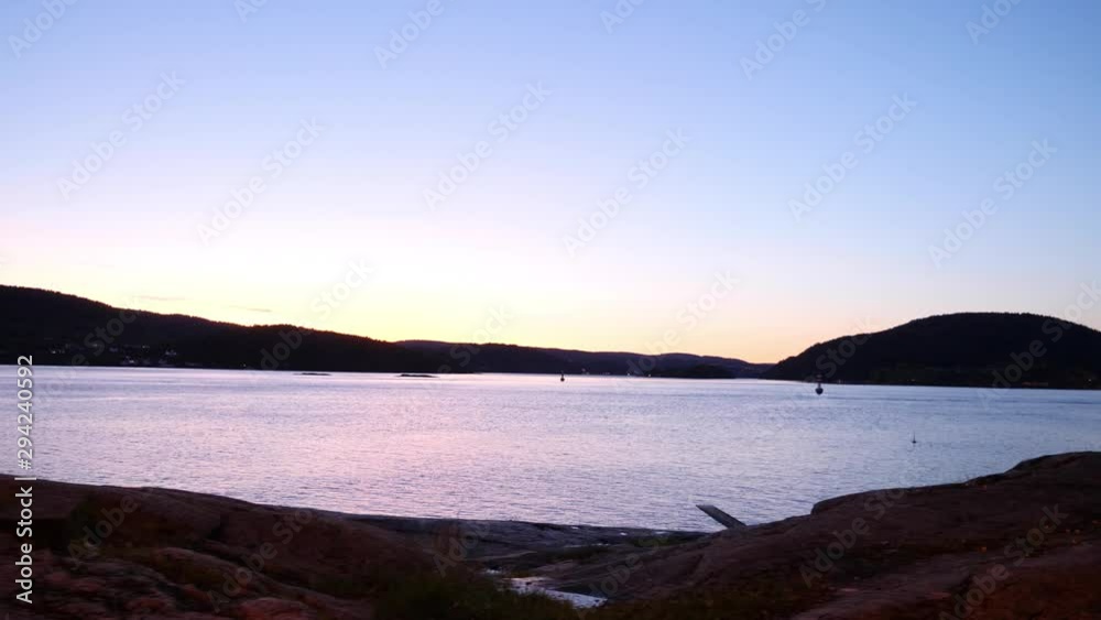 Sliding view of a vast body of water at sunset with mountians and hills in the distance Sliding view of a vast body of water at sunset with mountians and hills in the distance