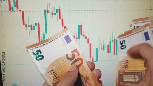 Female hands recount euro banknotes against the background of a monitor with a graph. photo