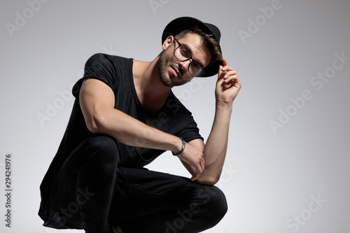 casual man standing crouched and fixing his hat