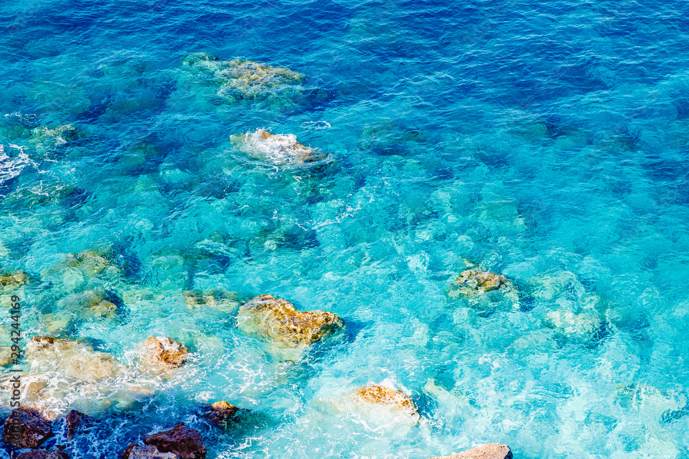 Fototapeta premium Blue emerald sea water with large stones beach. Rocky shore transparent turquoise bottom Malta