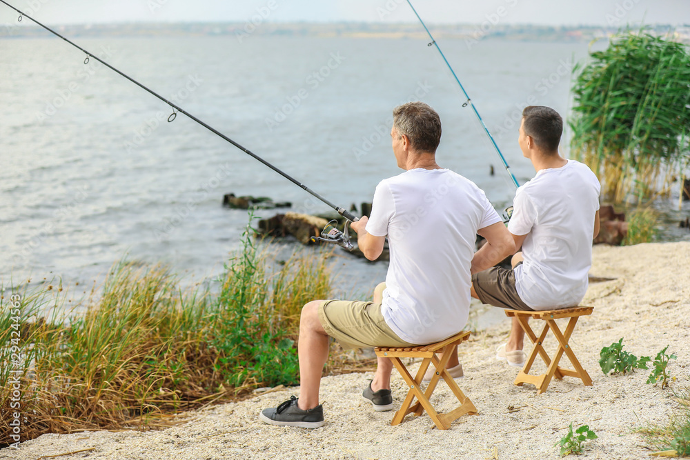 Young man and his father fishing on river