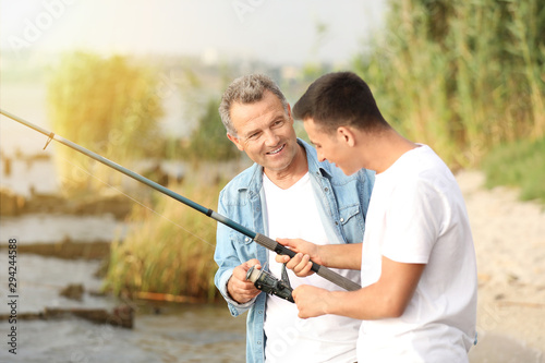 Young man and his father fishing on river