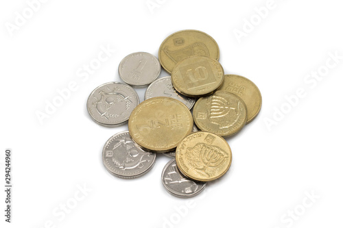 A close up, macro image of a pile of silver and gold coins from Israel shot against a white background