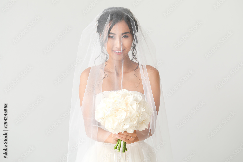 Beautiful young Asian bride on light background Beautiful young Asian bride on light background