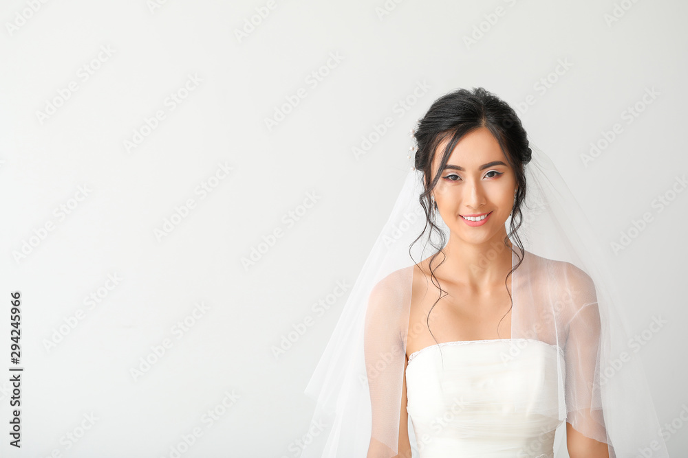 Beautiful young Asian bride on light background Beautiful young Asian bride on light background