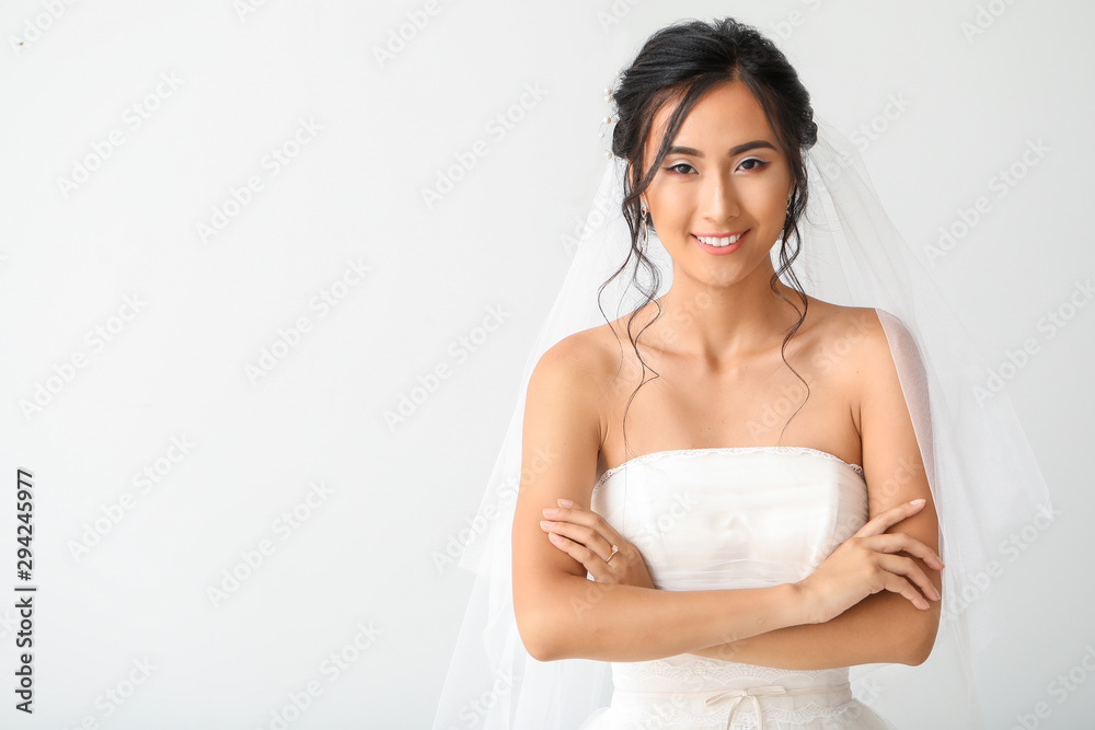 Beautiful young Asian bride on light background Beautiful young Asian bride on light background