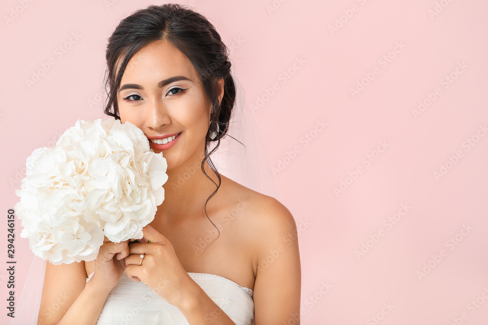 Beautiful young Asian bride on color background