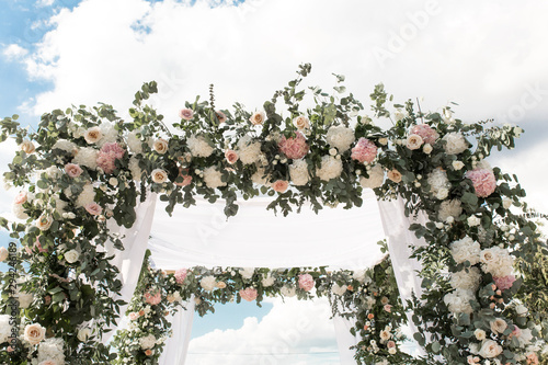 A festive chuppah decorated with fresh beautiful flowers for an outdoor wedding ceremony photo