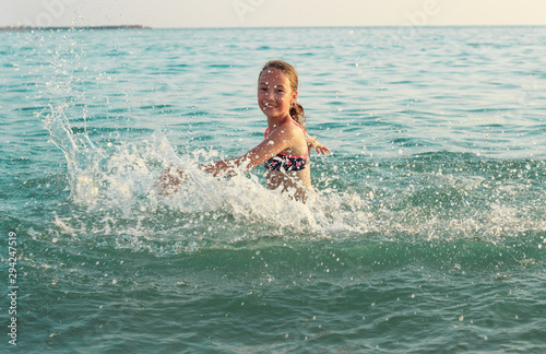 beautiful Teen Girl playing In Sea Waves. Jump Accompanied By Water Splashes. Summer Day, Happy childhood, Ocean Coast concept