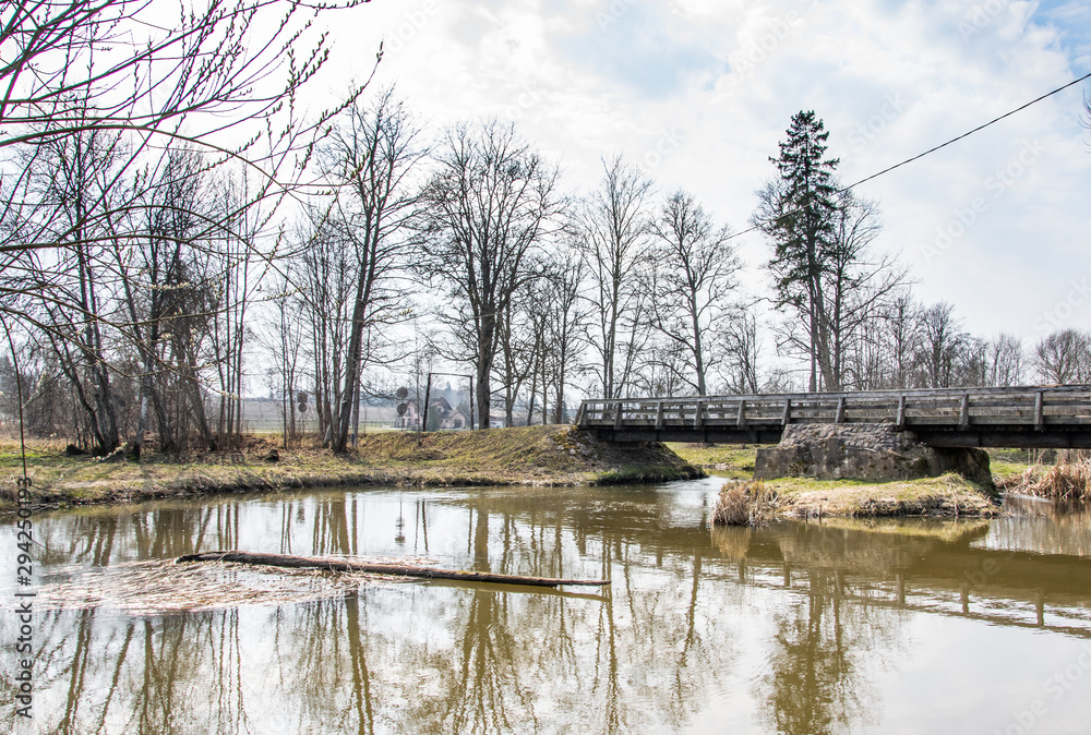 Spring landscape. A wooden bridge over a small river in early spring.