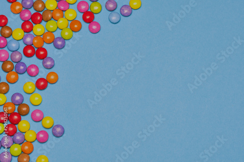 multicolored chocolate drops against blue background