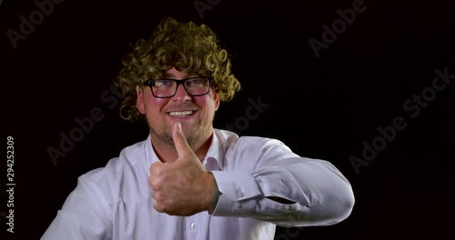 smiling man in curly fair haired wig raises thumb-up
