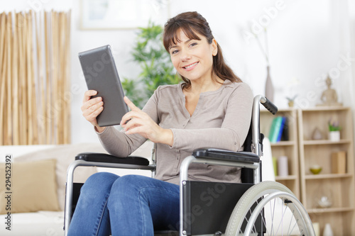 young disabled woman in wheelchair at home with tablet pc