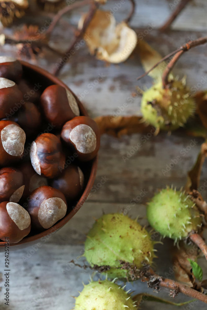 Chestnuts. A bowl of chestnuts. Leaves of a chestnut tree. Wood background. Selective focus. Chestnuts. A bowl of chestnuts. Leaves of a chestnut tree. Wood background. Selective focus.