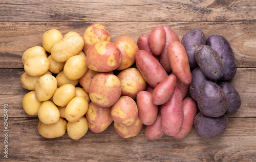 Heap of different types of potatoes on wooden rustic table photo