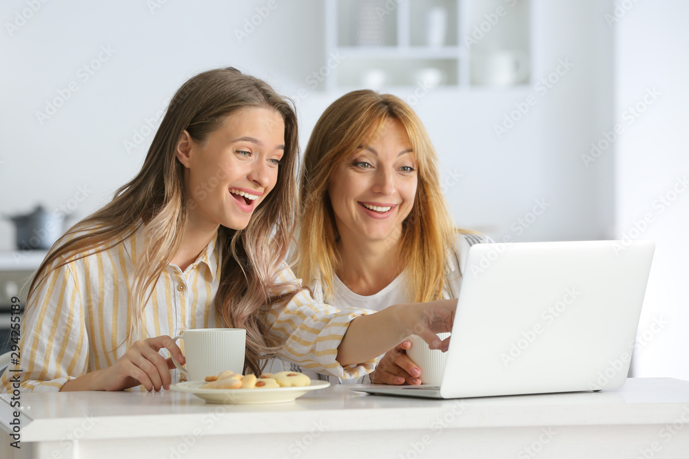 Happy mother and daughter with laptop in kitchen Happy mother and daughter with laptop in kitchen