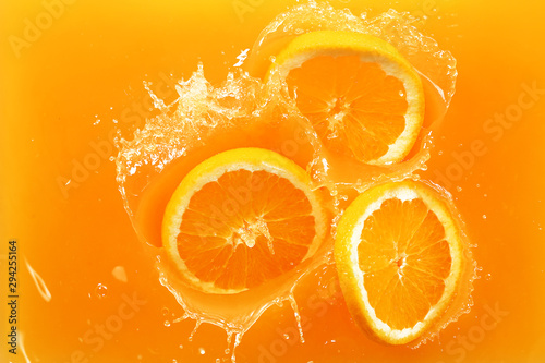 Falling of orange slices into juice, top view