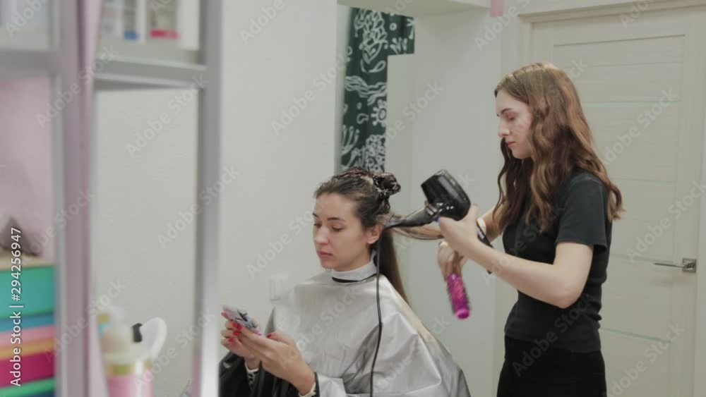 Girl hairdresser dries hair to client with hairdryer at hairdresser. Girl hairdresser dries hair to client with hairdryer at hairdresser.