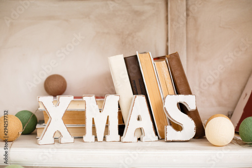 Christmas library. Room decorated for New Year. Wooden letters XMAS on a shelf with books
