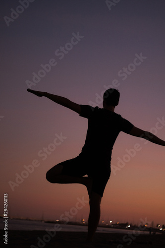 Silhouette of man doing yoga on the beach