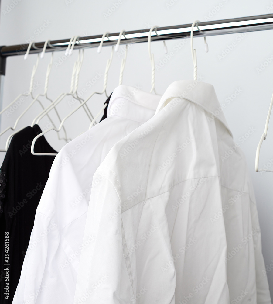 white men's crumpled shirts hanging on a metal hanger