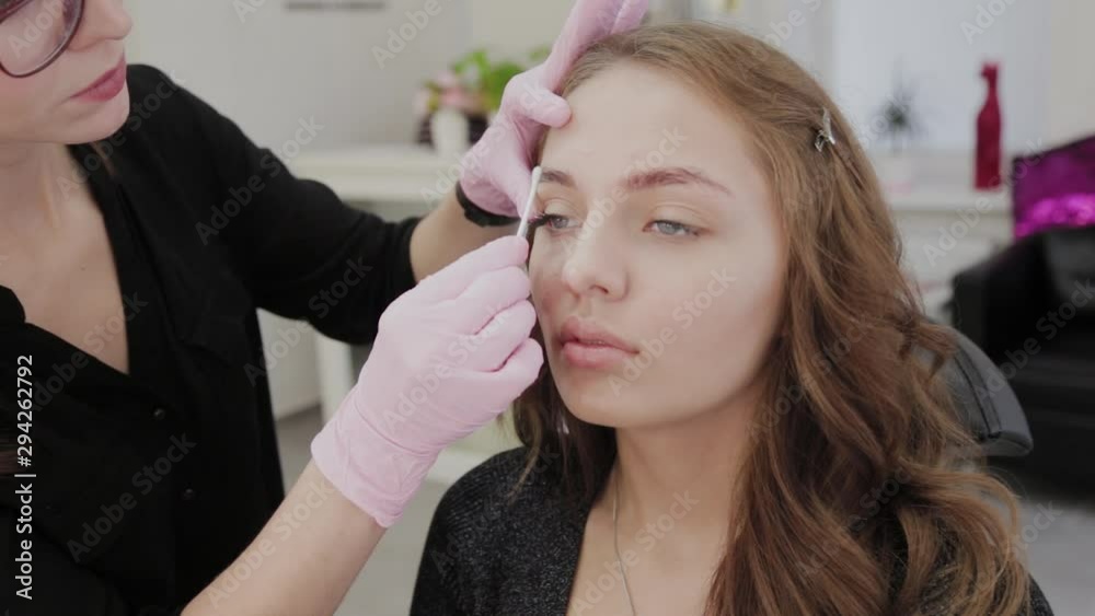 Makeup artist lubricates the eyebrows of the client with gel before the procedure. Makeup artist lubricates the eyebrows of the client with gel before the procedure.