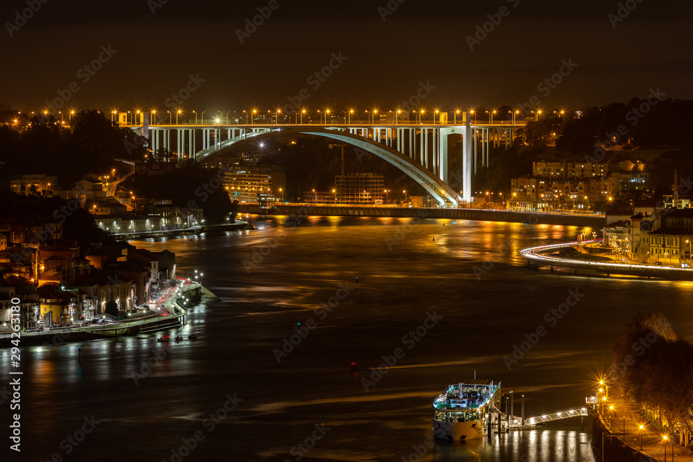 City of Porto at night, looking over Douro River with Arrabida Bridge at distance
