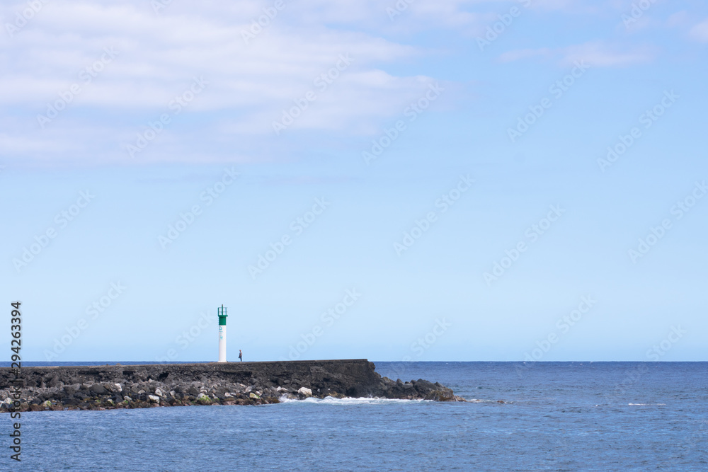 Lonely person standingnext to lighthouse at Saint Pierre harbor Réunion island