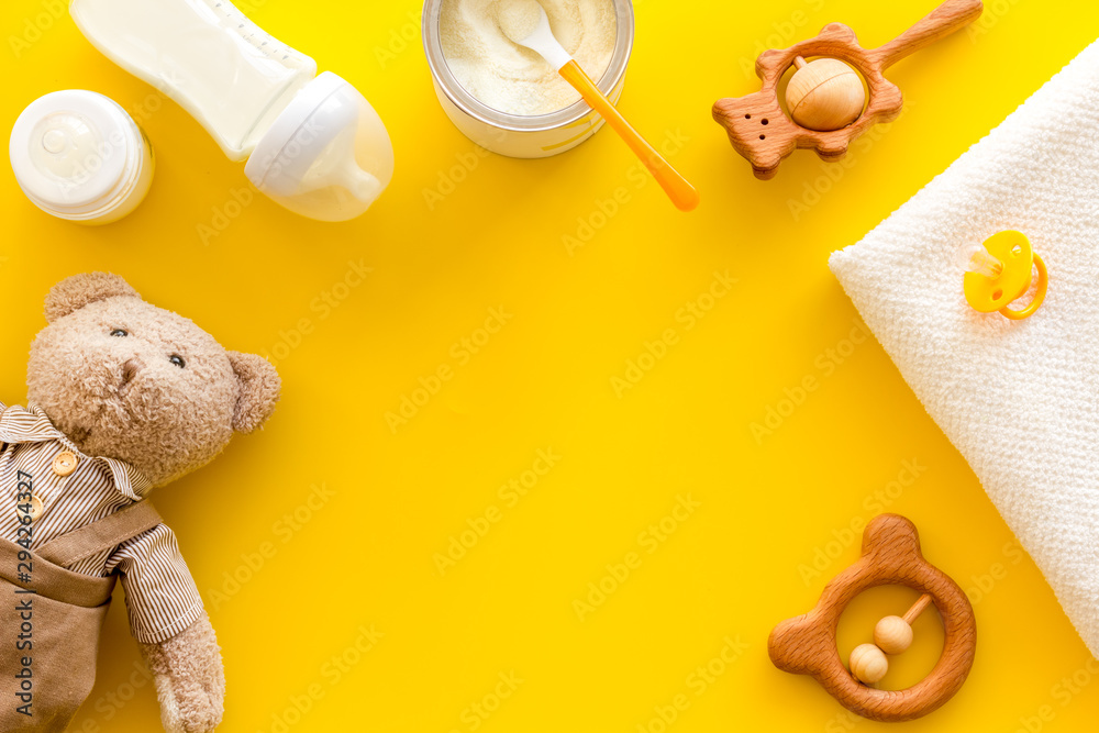 Baby food background with toys and accessories on yellow table top view pattern frame copy space