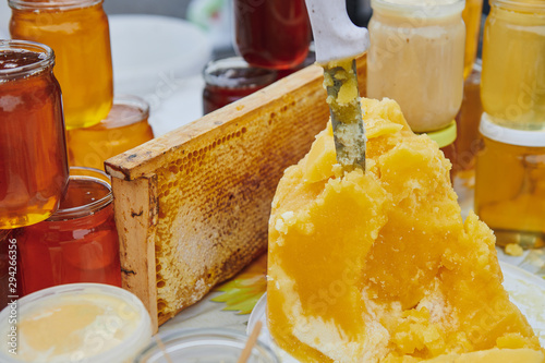 A lot of honey products at the market. Jars with different varieties of honey. The knife sticks out of honey. Honey farm products.