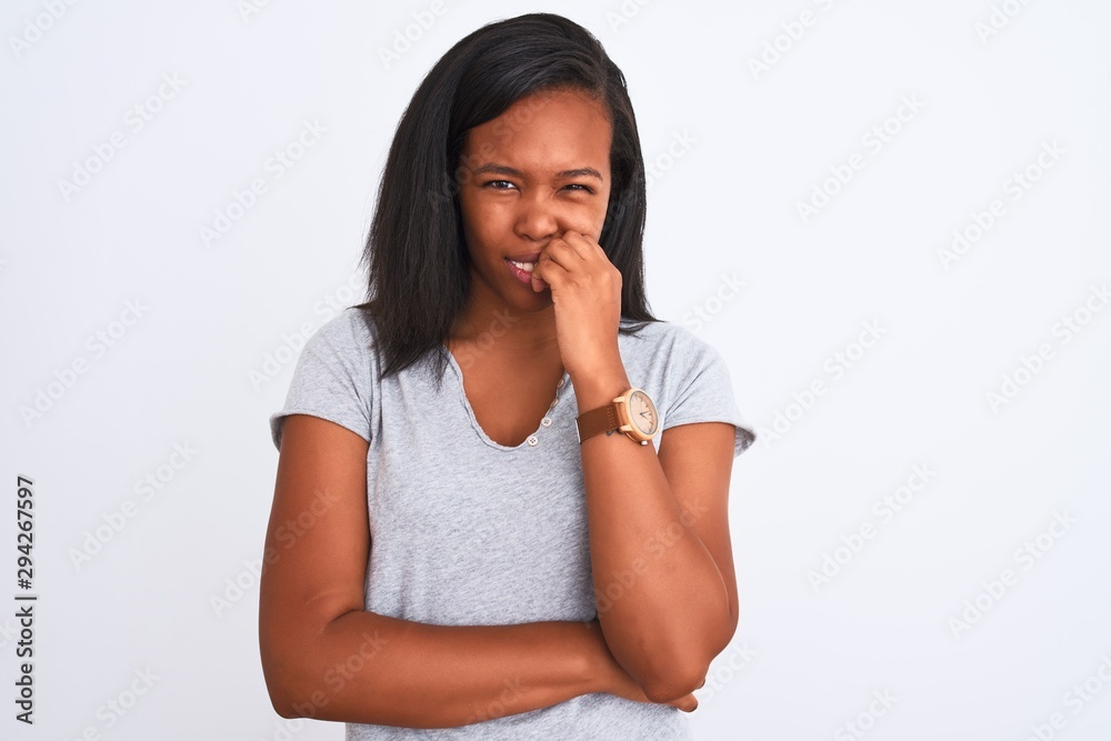 Beautiful young african american woman wearing casual t-shirt over isolated background looking stressed and nervous with hands on mouth biting nails. Anxiety problem. Beautiful young african american woman wearing casual t-shirt over isolated background looking stressed and nervous with hands on mouth biting nails. Anxiety problem.