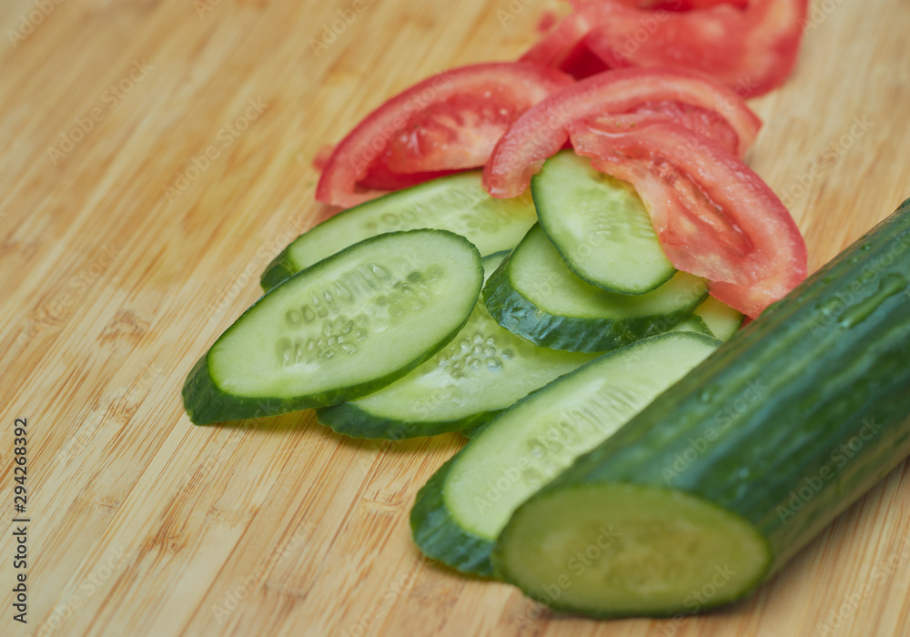 chopped cucumber and tomato on a cutting board. raw healthy vegetables. Vegetable salad. chopped cucumber and tomato on a cutting board. raw healthy vegetables. Vegetable salad.