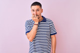 Young handsome man wearing nautical striped t-shirt over pink isolated background looking stressed and nervous with hands on mouth biting nails. Anxiety problem.