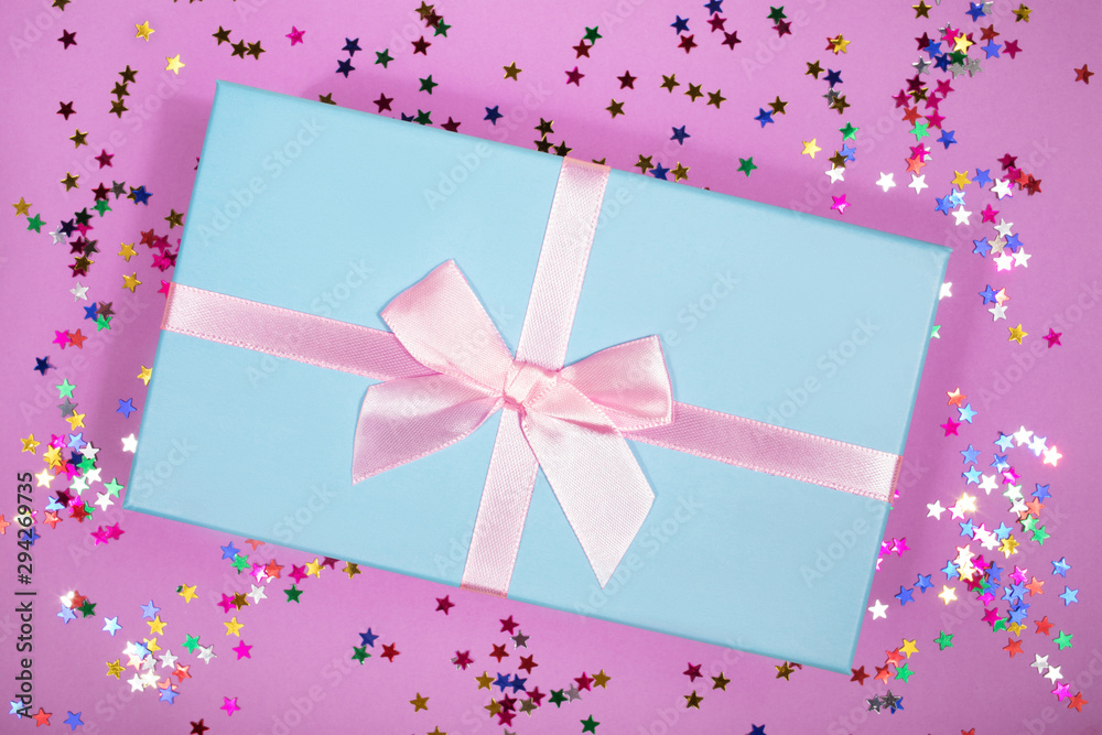 Beautiful gift box with atlas ribbon on purple background with sparkling stars, festive concept