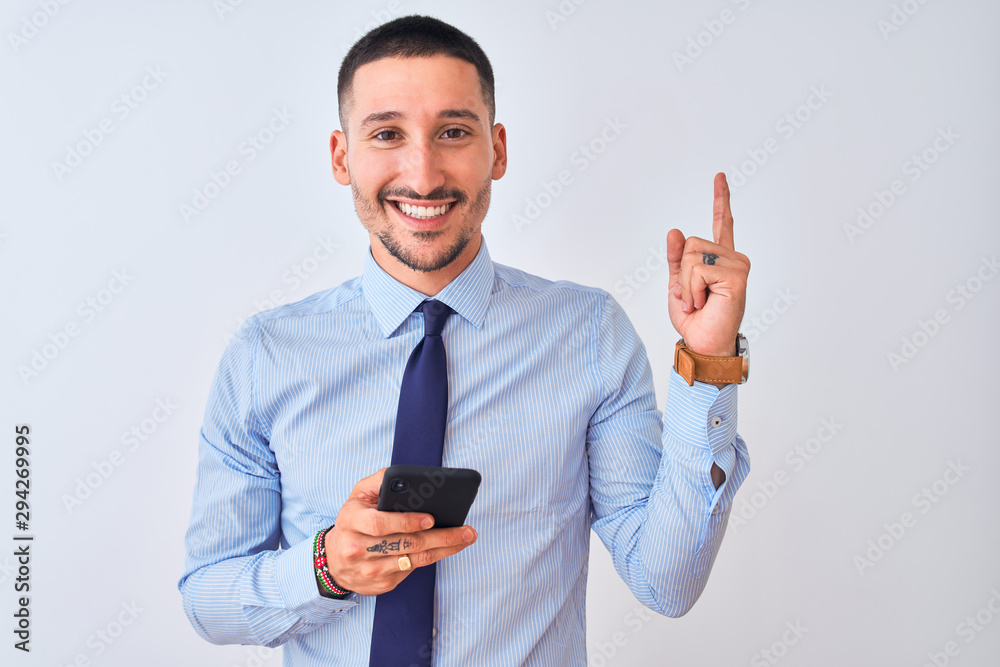 Young handsome business man using smartphone over isolated background very happy pointing with hand and finger to the side Young handsome business man using smartphone over isolated background very happy pointing with hand and finger to the side