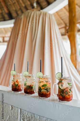 Set of four strawberry mojito cocktails. Slice of lime  glass bottle  black straw. Summer cold drink  vacations concept.