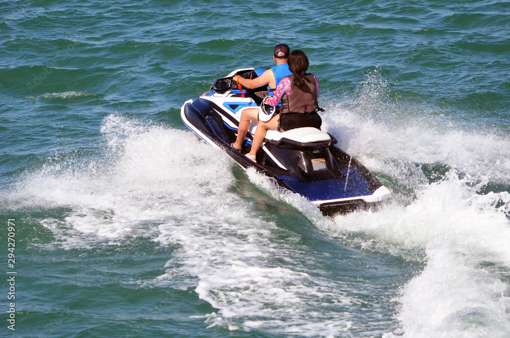 Couple riding tandem on a speeding jetski Couple riding tandem on a speeding jetski