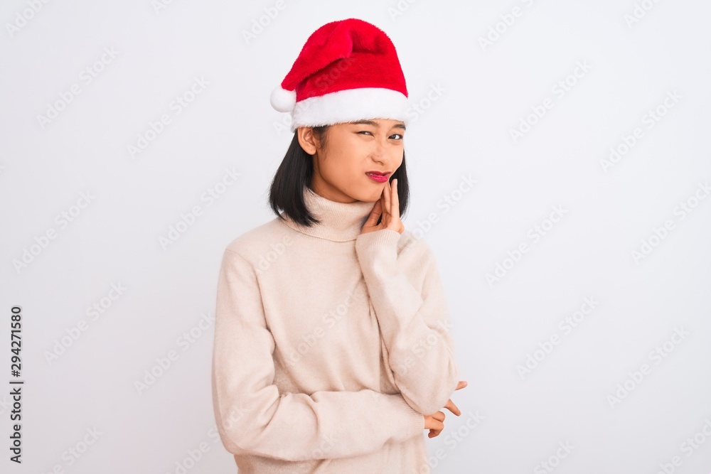 Young beautiful chinese woman wearing Christmas Santa hat over isolated white background touching mouth with hand with painful expression because of toothache or dental illness on teeth Young beautiful chinese woman wearing Christmas Santa hat over isolated white background touching mouth with hand with painful expression because of toothache or dental illness on teeth