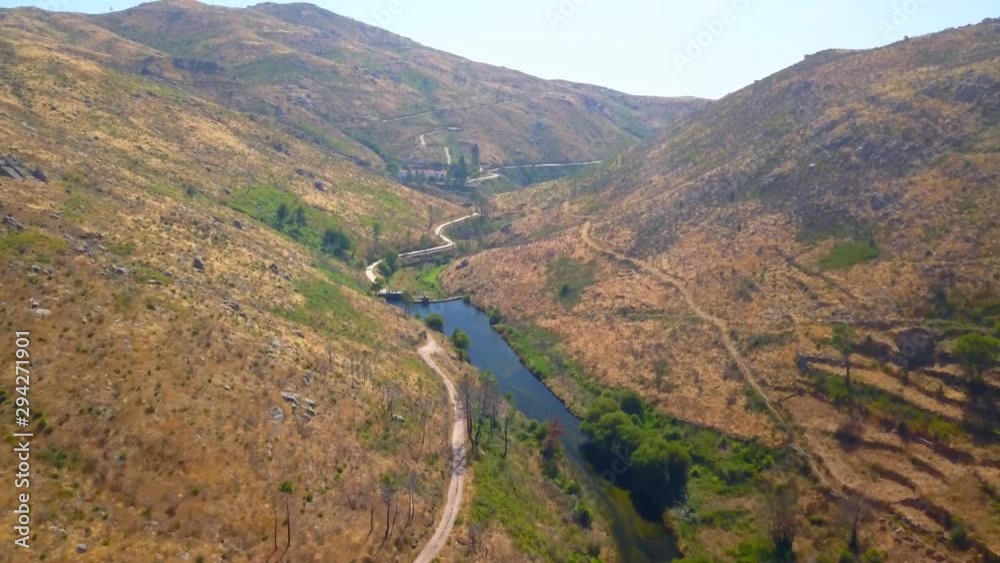 Aerial, drone shot, overlooking a winding road, a river and nature, in a valley, at Vale Glaciar, in Serra da Estrela natural park, on a sunny day, in Portugal Aerial, drone shot, overlooking a winding road, a river and nature, in a valley, at Vale Glaciar, in Serra da Estrela natural park, on a sunny day, in Portugal