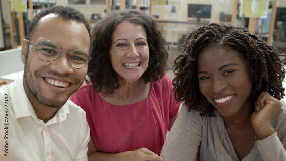 Smiling people posing for self portrait at library. Handsome African American man with outstretched arm posing with cheerful women. View from camera. Concept of self portrait Smiling people posing for self portrait at library. Handsome African American man with outstretched arm posing with cheerful women. View from camera. Concept of self portrait