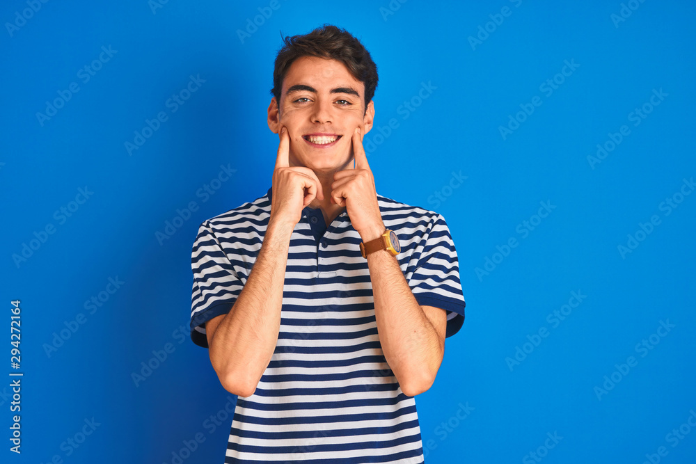 Teenager boy wearing casual t-shirt standing over blue isolated background Smiling with open mouth, fingers pointing and forcing cheerful smile Teenager boy wearing casual t-shirt standing over blue isolated background Smiling with open mouth, fingers pointing and forcing cheerful smile