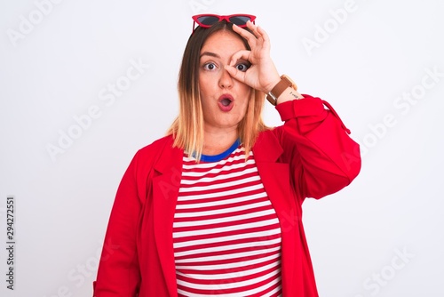 Young beautiful woman wearing striped t-shirt and jacket over isolated white background doing ok gesture shocked with surprised face, eye looking through fingers. Unbelieving expression.