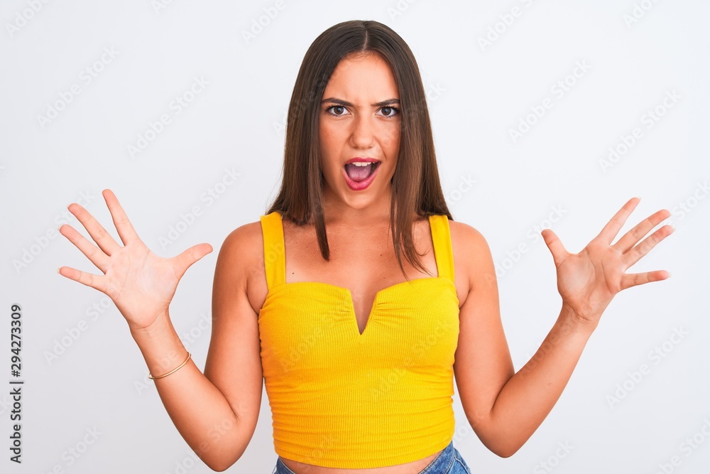 Fototapeta premium Young beautiful girl wearing yellow casual t-shirt standing over isolated white background celebrating crazy and amazed for success with arms raised and open eyes screaming excited. Winner concept